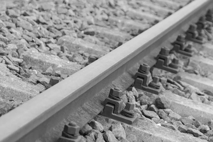 银色金属列车轨道上的黑色金属螺栓用灰色石头包裹