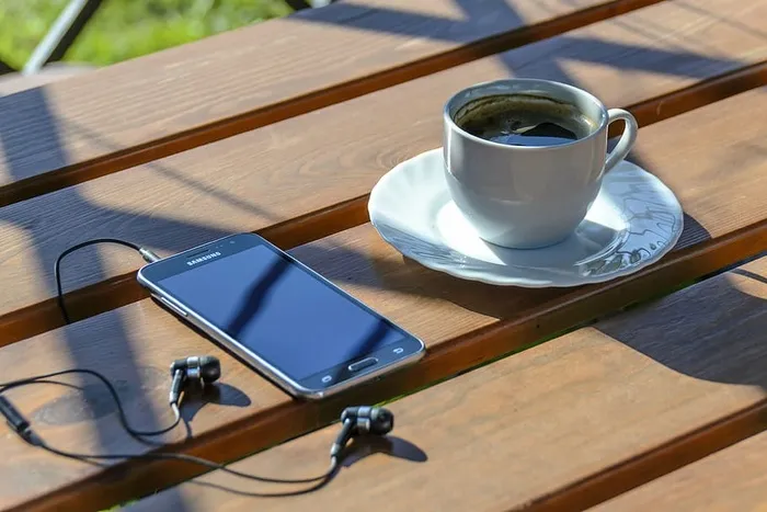 黑色，三星安卓智能手机，关闭屏幕，旁边，杯子，咖啡，上衣，棕色