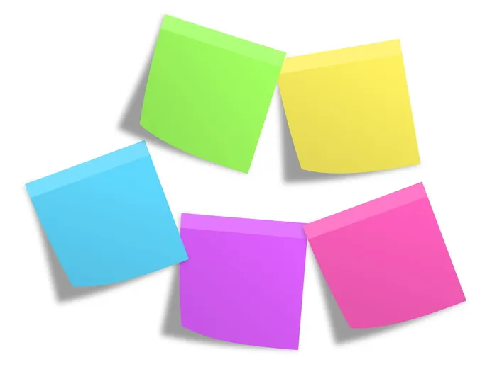 粉红色、绿色、黄色、蓝色和紫色的便笺贴在白色的墙上