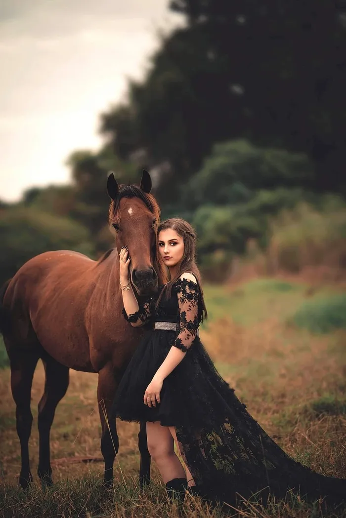 一名女子在马旁穿着黑色连衣裙的照片