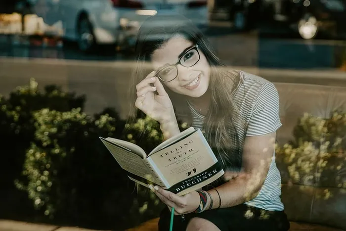 戴着黑色眼镜微笑看书的女人