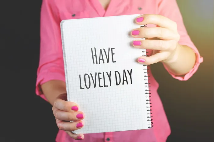 一位身穿粉红色连衣裙的女士拿着一本带有可爱的日牌的绘图笔记本
