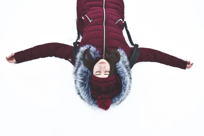 张开双臂躺在雪地上的女人