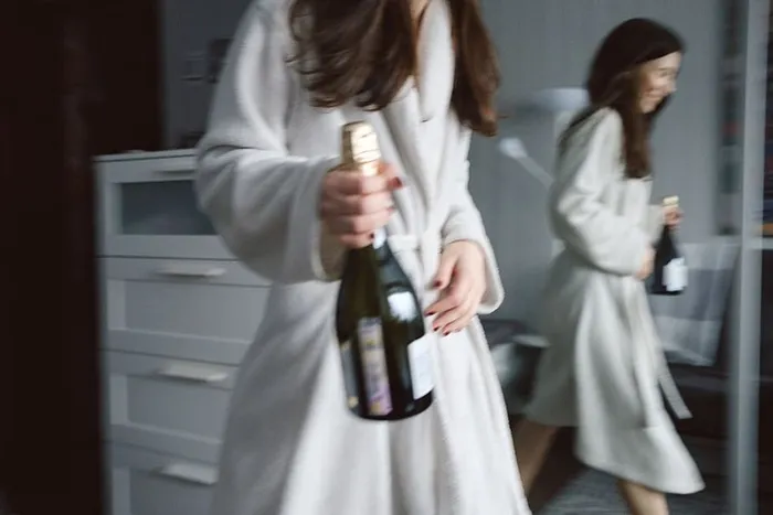 身穿白袍的女子拿着酒瓶的照片
