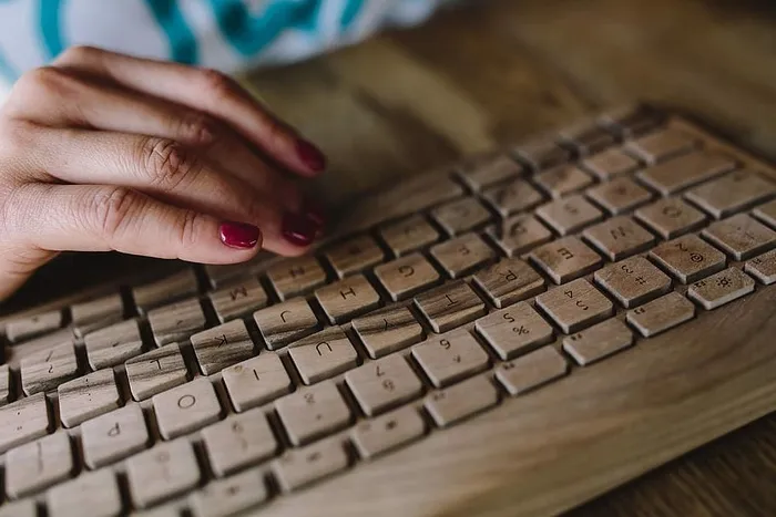 女性手在无线木质键盘上打字的特写