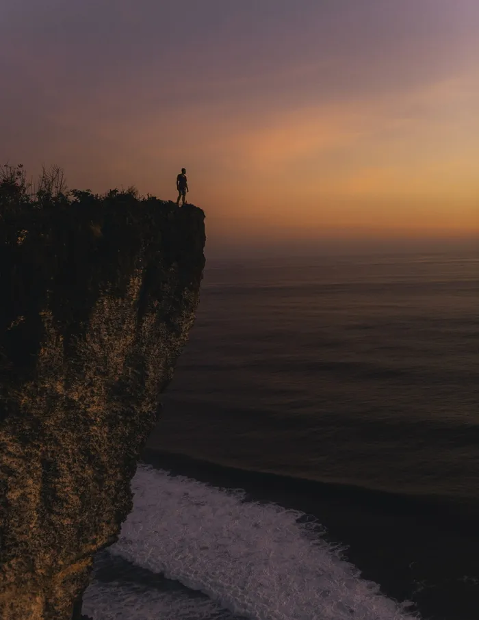 日落时站在悬崖上的人