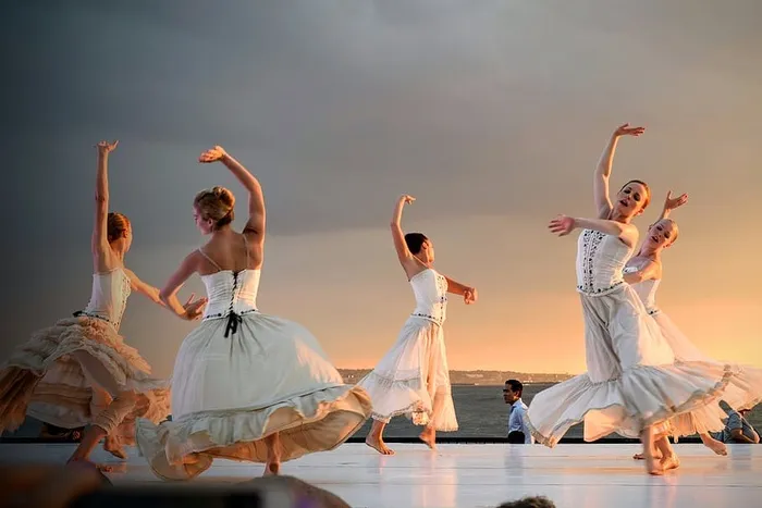 日落时，5名身穿白色连衣裙的女子在灰色的天空下跳舞