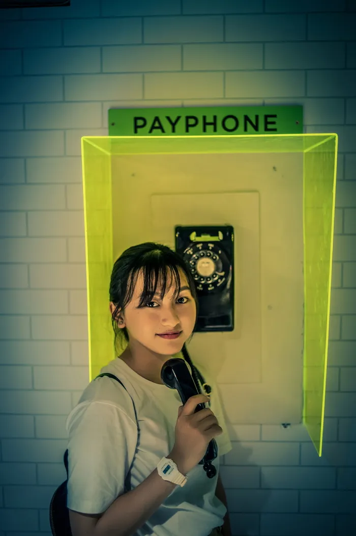 一名女子站在公用电话旁的照片。