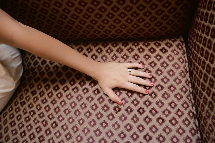 一个擦着红色指甲油的女人的手放在沙发上