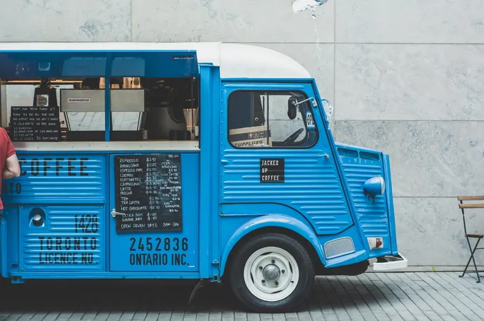 蓝色食品车，蓝色，白色，咖啡车，停车，水泥墙，白天，公共汽车