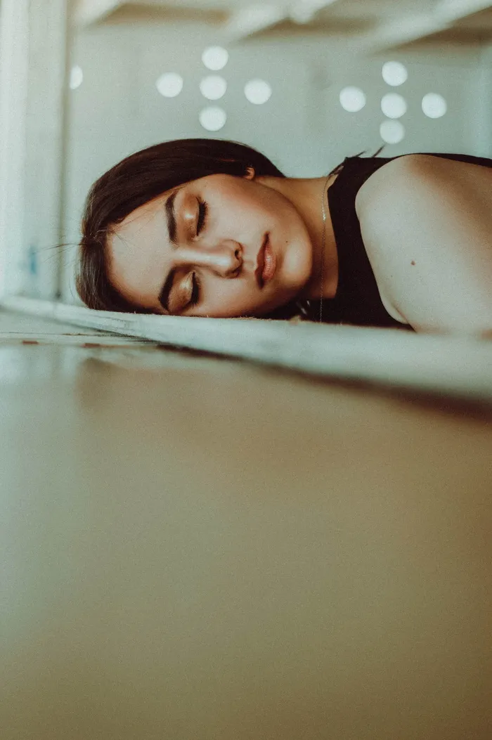 一名女子把头靠在棕色木板床上，闭上眼睛
