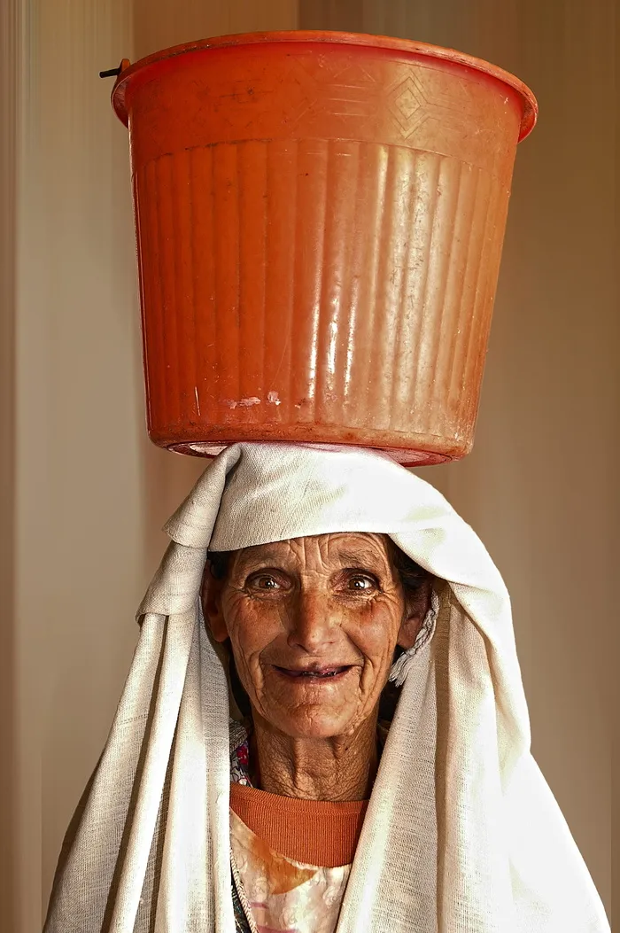 一名妇女头上顶着橙色塑料桶的肖像照片
