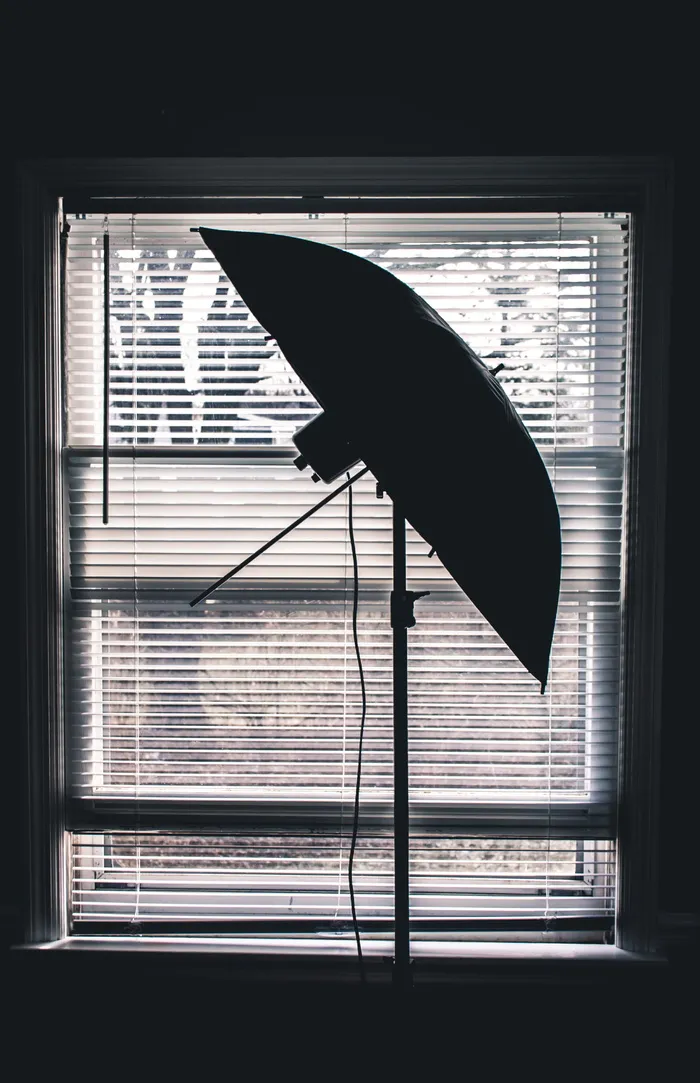 室内白色百叶窗附近工作室伞的剪影照片