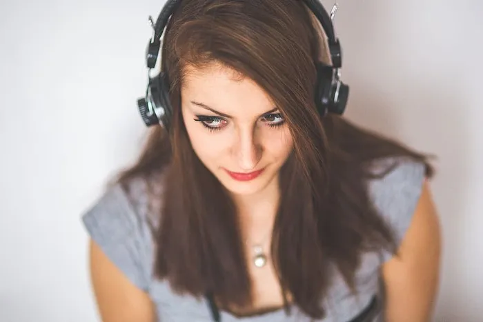 年轻迷人的女孩戴着耳机听音乐的照片