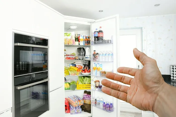图为现代厨房中手指向打开的冰箱的示意图