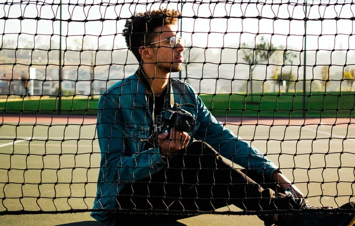 男子坐在网球场上的照片