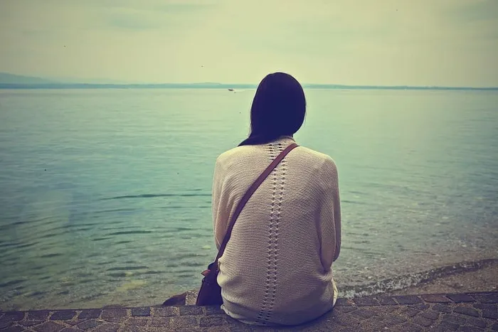 女人，坐着，棕色，水泥，路面，海洋，白天，白色
