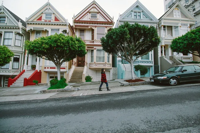 女人走向停在五颜六色的房子前的黑色轿车