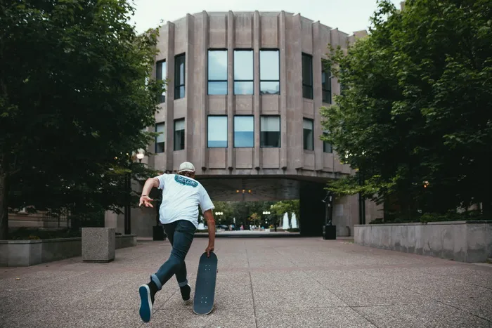 一名年轻的白人滑板运动员在一栋建筑的校园里起步