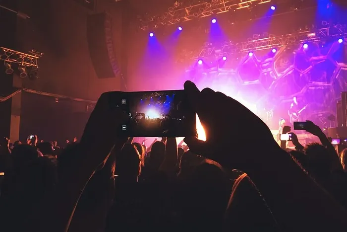 在音乐节上，人群中的一位个人摄影师正在用手机拍照