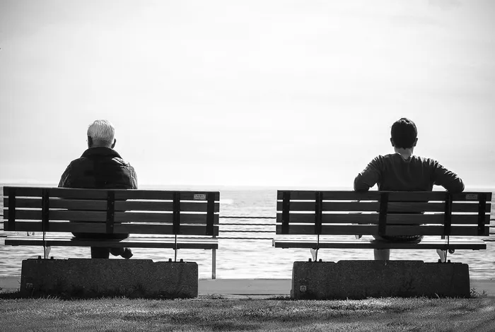 灰度照片2人坐在海边的单独长椅上