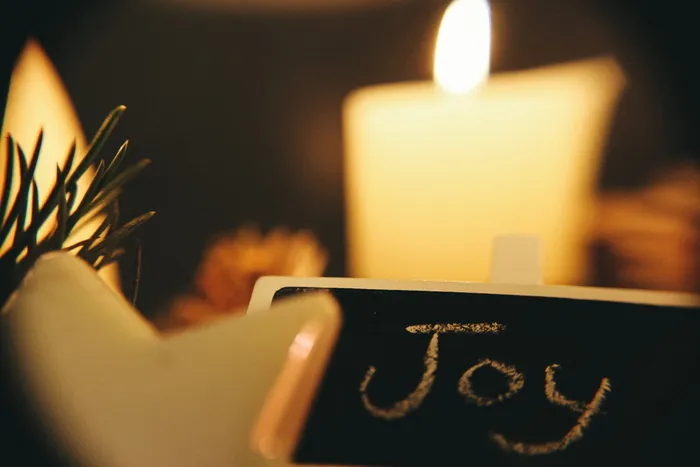 用白色粉笔写着“欢乐”的黑色黑板，背景是白色蜡烛。