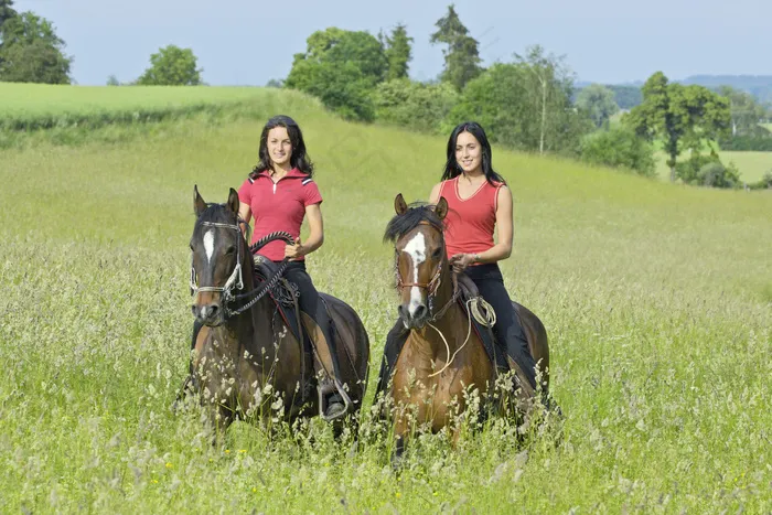 草地上两个骑马的女孩图片