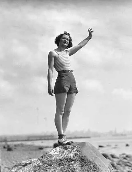 泳装的妇女挥动，当站立在海滩，可能华盛顿州的一块大岩石上时