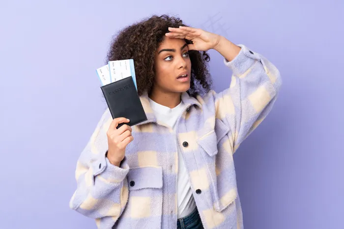 一位年轻的非洲裔美国妇女在度假时拿着护照和机票在远处寻找