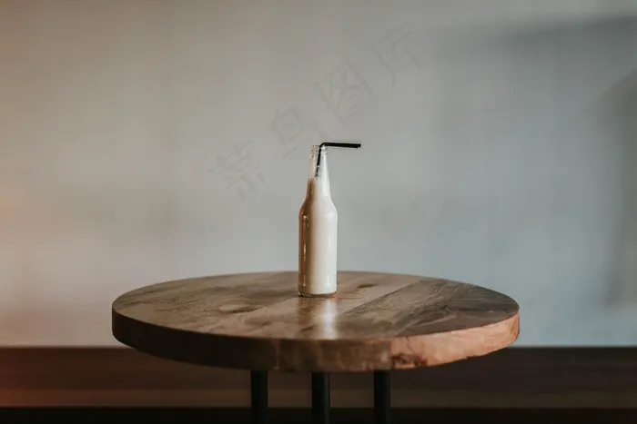 一个装有黑色吸管的玻璃瓶在棕色的木桌上装满了饮料