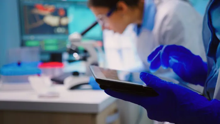 关闭科学家在平板电脑上写作，而生物学家团队深夜在 backgorund 显微镜下进行生物研究