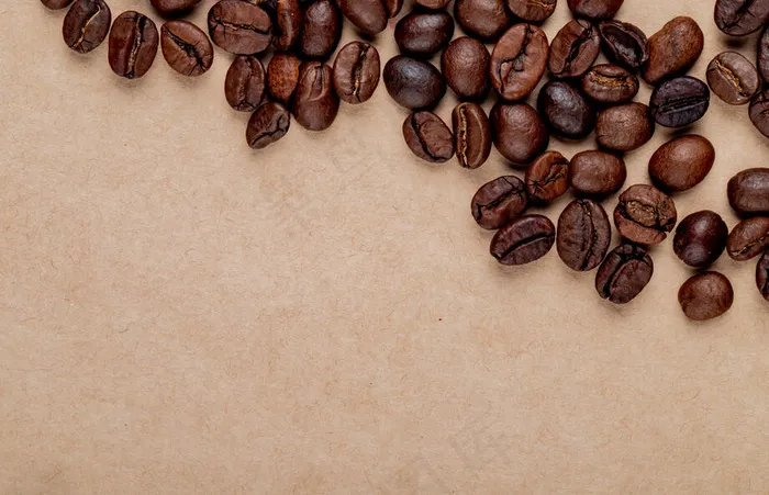 烘焙咖啡豆的俯视图散落在牛皮纸纹理背景上，带有复印空间