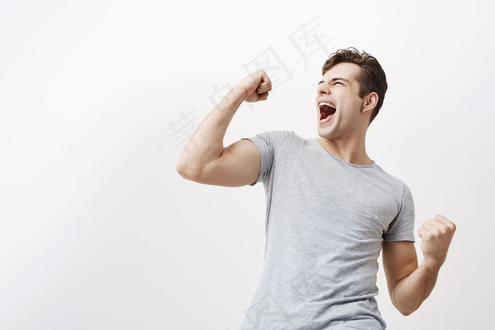 成功的情绪化的年轻白种男运动员黑发尖叫是举起握紧的拳头在空中感到