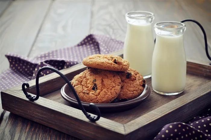 精美家居餐桌木板上的葡萄曲奇饼干和新鲜牛奶早餐
