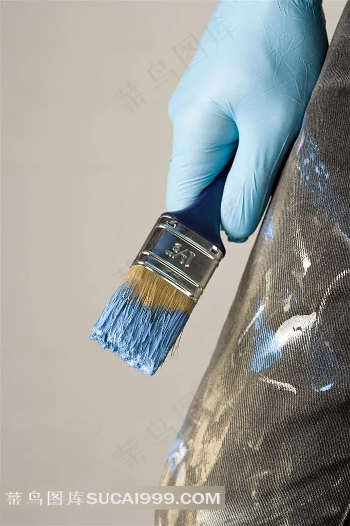 戴着蓝色手套拿着刷子的油漆工人