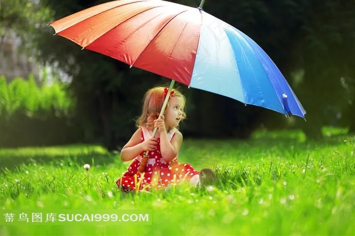撑着彩虹伞坐在草地上的小女孩