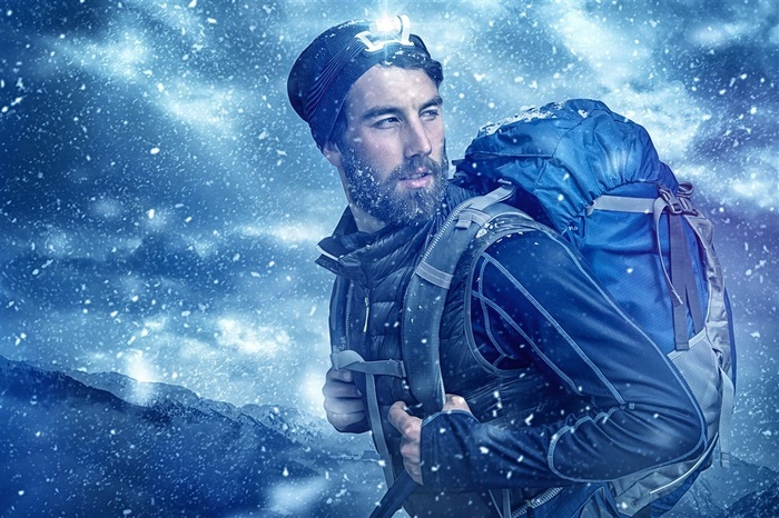 风雪中背着运动背包的探险人物高清图片