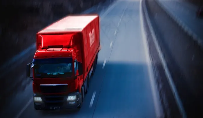 高速路上高速行驶的红色货车高清图片