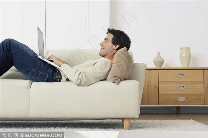 数码生活-躺在沙发上使用笔记本电脑的外国男人