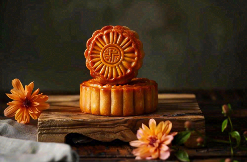 中国传统美食月饼中秋节菊花摆盘黑色背景摄影图