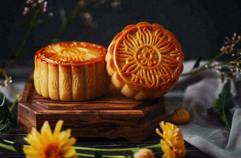 中国传统美食月饼中秋节菊花摆盘黑色背景摄影图