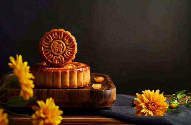 中国传统美食月饼中秋节菊花摆盘黑色背景摄影图